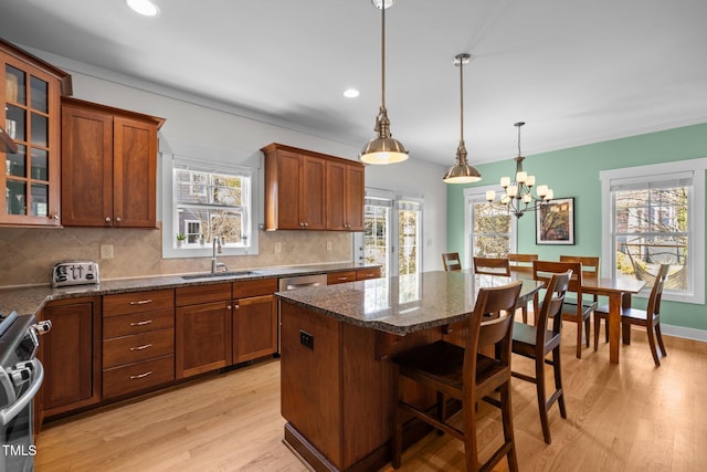 kitchen with light wood-type flooring, a sink, stainless steel range oven, and tasteful backsplash