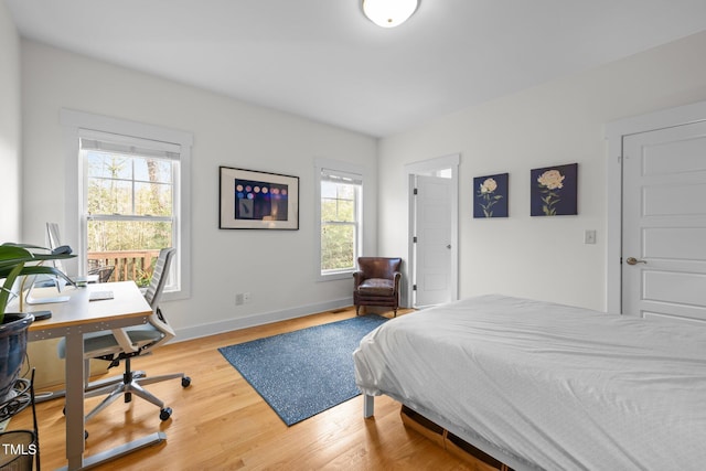 bedroom featuring baseboards, multiple windows, and wood finished floors