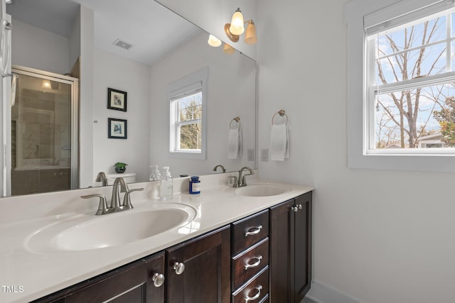 full bathroom with visible vents, a sink, a stall shower, and double vanity