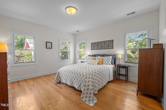 bedroom with baseboards, multiple windows, and light wood finished floors