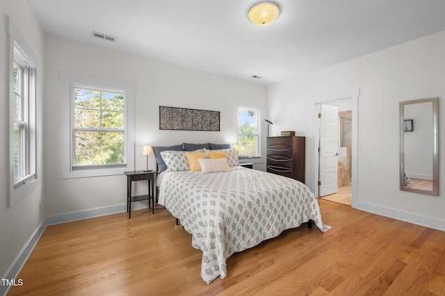bedroom with light wood-style floors, multiple windows, and visible vents