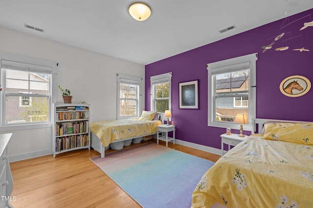 bedroom featuring visible vents, light wood-style floors, and baseboards