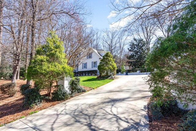 view of property exterior featuring concrete driveway and a yard