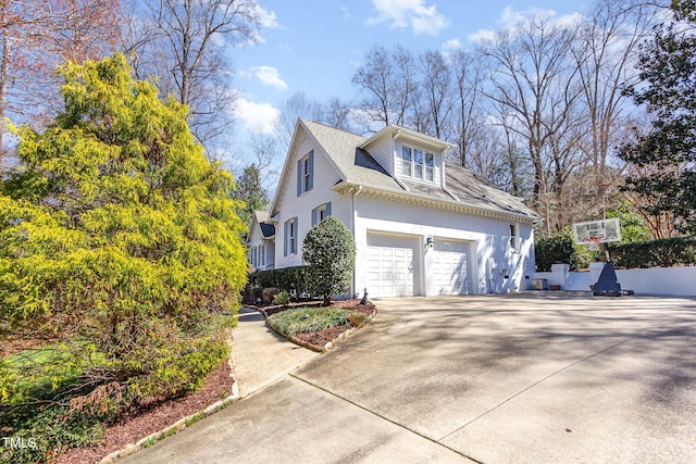 view of side of home with stucco siding, an attached garage, and concrete driveway