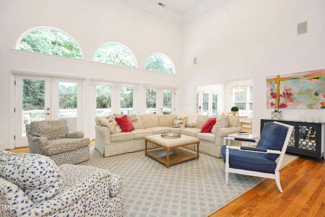 living room featuring wood finished floors, an inviting chandelier, ornamental molding, french doors, and a wealth of natural light