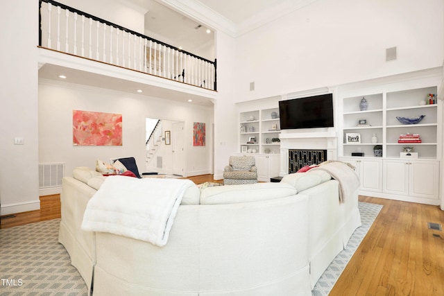 living area featuring stairs, crown molding, visible vents, and light wood-type flooring