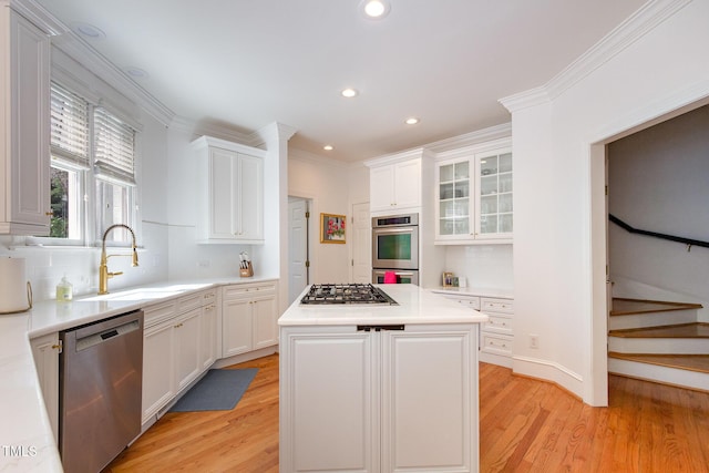 kitchen featuring appliances with stainless steel finishes, white cabinetry, light wood-type flooring, and a sink