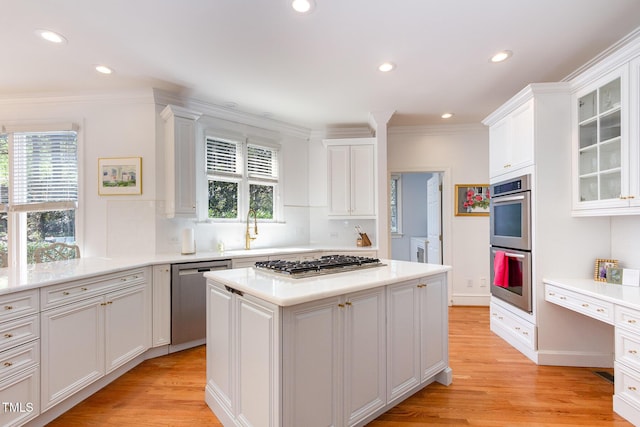 kitchen with light countertops, appliances with stainless steel finishes, plenty of natural light, white cabinetry, and a sink