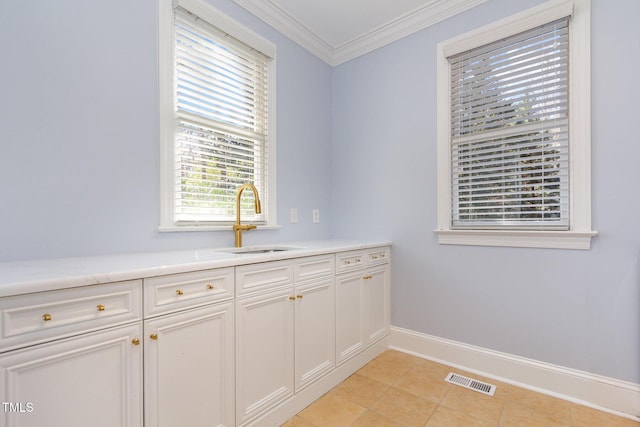 laundry area featuring visible vents, baseboards, light tile patterned flooring, ornamental molding, and a sink