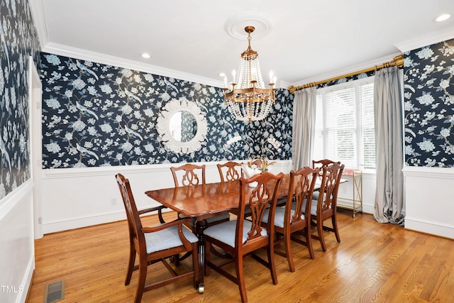 dining room with a chandelier, visible vents, light wood-type flooring, and crown molding