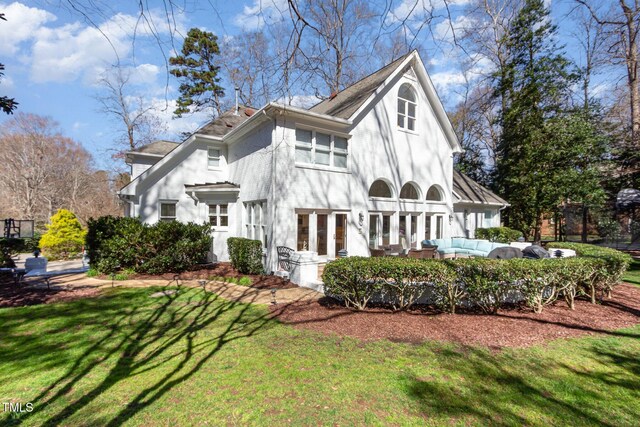 view of side of home featuring an outdoor living space, a lawn, and stucco siding