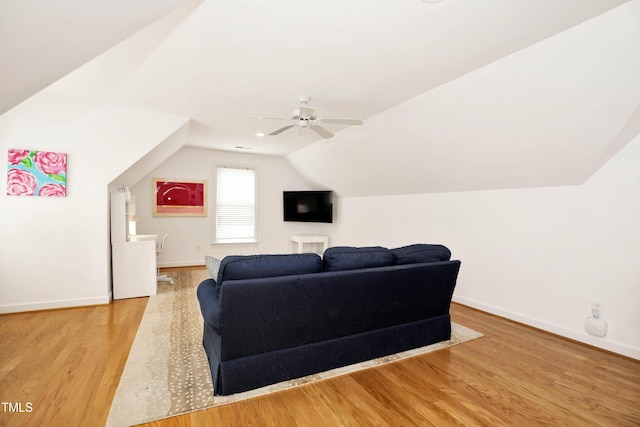 living room featuring vaulted ceiling, a ceiling fan, baseboards, and wood finished floors