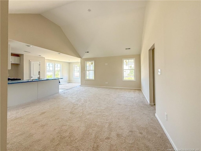 4010 Racking Horse Rd, Hope Mills, NC 28348 - unfurnished living room with light colored carpet, high vaulted ceiling, plenty of natural light, and baseboards