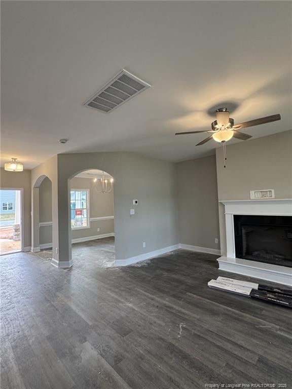150 Ziggy Way, Raeford, NC 28376 - unfurnished living room with arched walkways, dark wood-type flooring, a fireplace with raised hearth, a chandelier, and ceiling fan