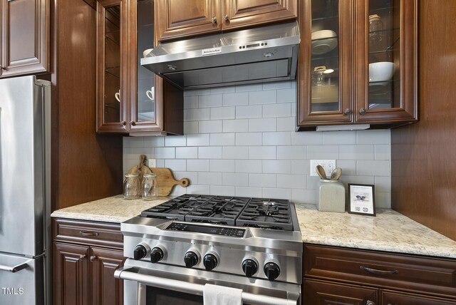 10529 Sablewood Dr Unit 111, Raleigh, NC 27617 - kitchen with appliances with stainless steel finishes, extractor fan, backsplash, glass insert cabinets, and light stone counters