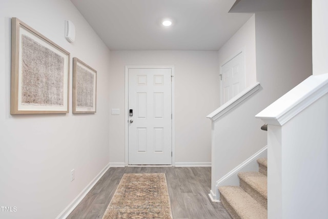 entryway featuring wood finished floors, baseboards, and stairway