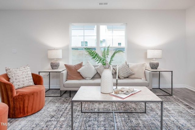 living area with visible vents, baseboards, and wood finished floors