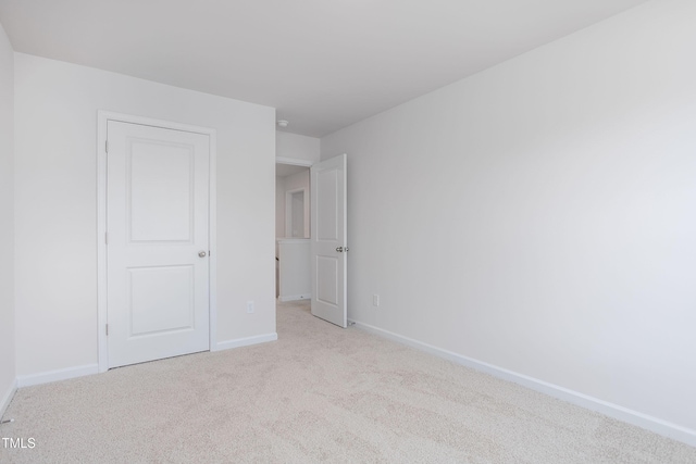 unfurnished bedroom with light colored carpet and baseboards