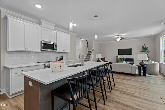20 Diamond Creek Dr, Zebulon, NC 27597 - kitchen featuring stainless steel microwave, crown molding, white cabinetry, a ceiling fan, and a kitchen breakfast bar