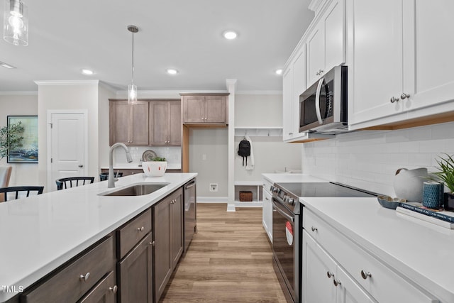 20 Diamond Creek Dr, Zebulon, NC 27597 - kitchen featuring appliances with stainless steel finishes, light countertops, crown molding, decorative light fixtures, and light wood-type flooring