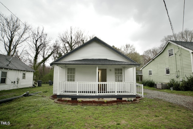 view of front of house featuring covered porch, a front yard, and roof with shingles
