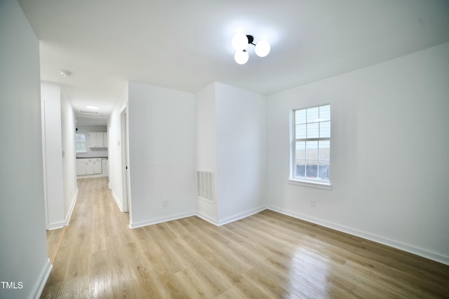 spare room featuring visible vents, light wood-style flooring, and baseboards