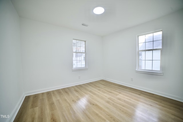 unfurnished room featuring wood finished floors, visible vents, and baseboards