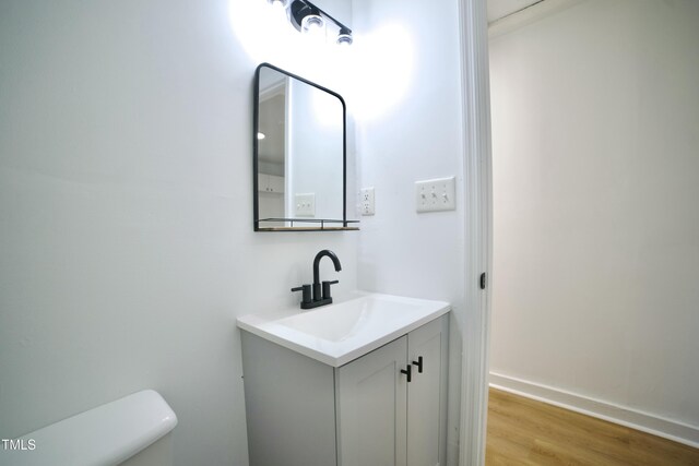 bathroom with toilet, wood finished floors, and vanity