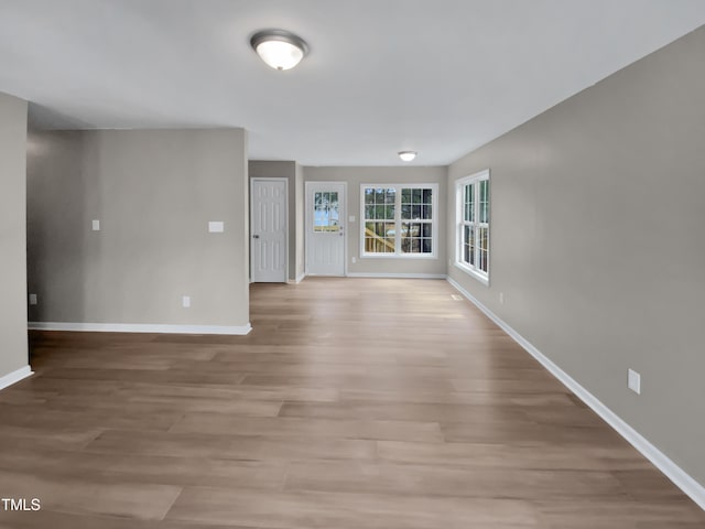 unfurnished living room with light wood-type flooring and baseboards