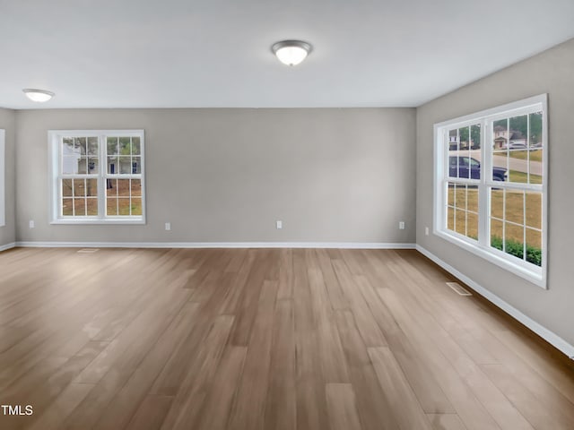 unfurnished room featuring visible vents, baseboards, and wood finished floors