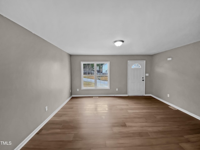 foyer entrance featuring visible vents, baseboards, and wood finished floors