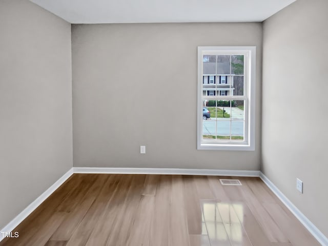 empty room with visible vents, baseboards, and wood finished floors