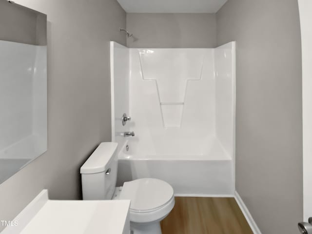 bathroom with toilet, shower / washtub combination, wood finished floors, baseboards, and vanity