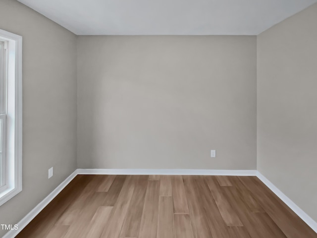 spare room featuring baseboards and wood finished floors