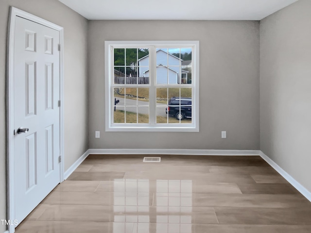 empty room featuring visible vents, baseboards, and wood finished floors