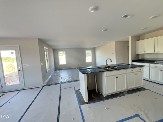 92 Dalton Dr, Lumber Bridge, NC 28357 - kitchen with baseboards, open floor plan, an island with sink, white cabinets, and a sink