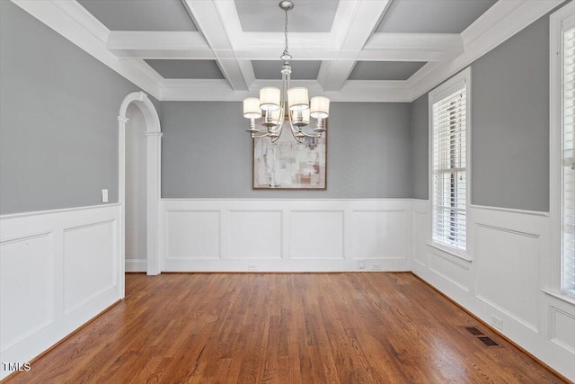 unfurnished dining area with visible vents, wood finished floors, beam ceiling, an inviting chandelier, and coffered ceiling