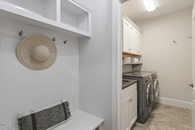 washroom with cabinet space, separate washer and dryer, and baseboards