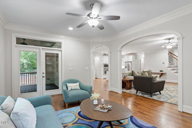 living area featuring stairs, arched walkways, ceiling fan, and wood finished floors