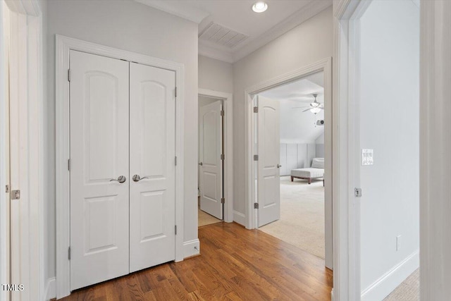 corridor with recessed lighting, baseboards, wood finished floors, visible vents, and ornamental molding