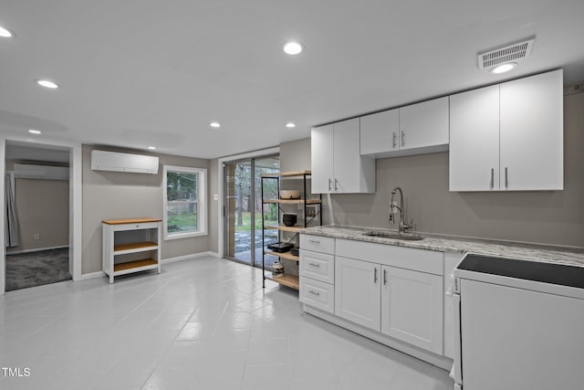 kitchen with visible vents, stove, an AC wall unit, a wall mounted AC, and a sink