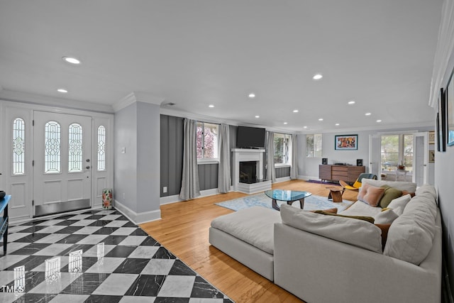 living area with crown molding, recessed lighting, baseboards, and a fireplace with raised hearth