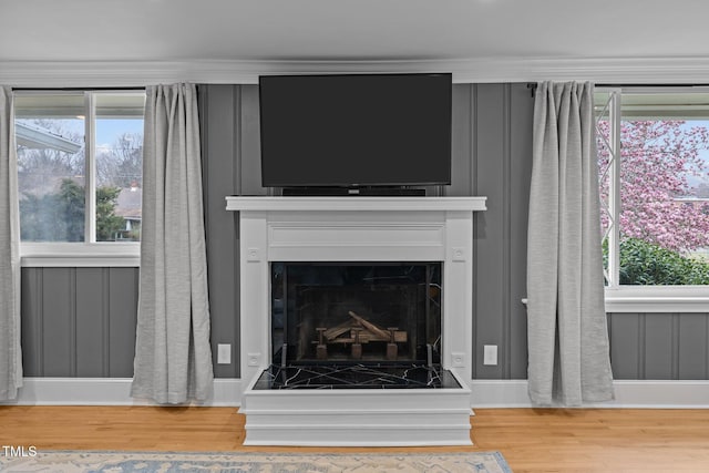 interior details with a fireplace with raised hearth, baseboards, and wood finished floors