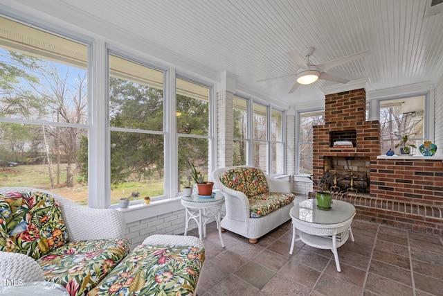 sunroom / solarium featuring a ceiling fan and a fireplace