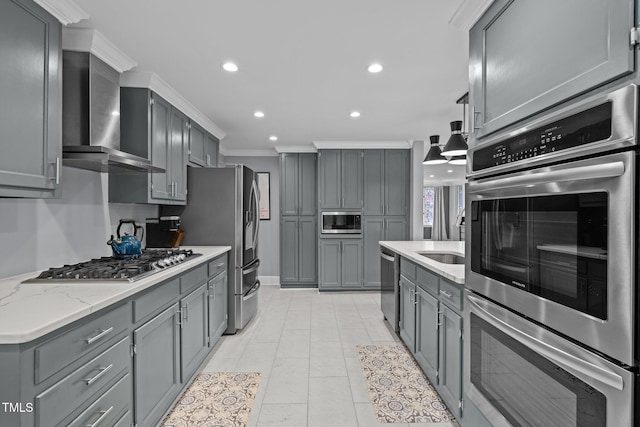 kitchen featuring wall chimney range hood, appliances with stainless steel finishes, ornamental molding, and gray cabinets