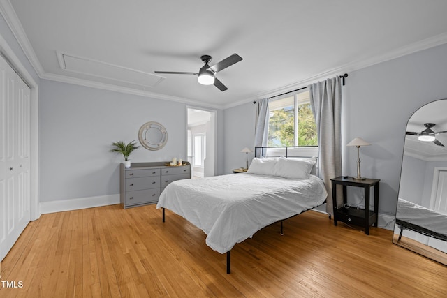 bedroom with crown molding, attic access, baseboards, light wood-type flooring, and a closet