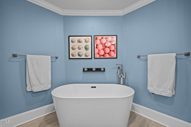 full bath featuring baseboards, a freestanding bath, ornamental molding, and wood finished floors