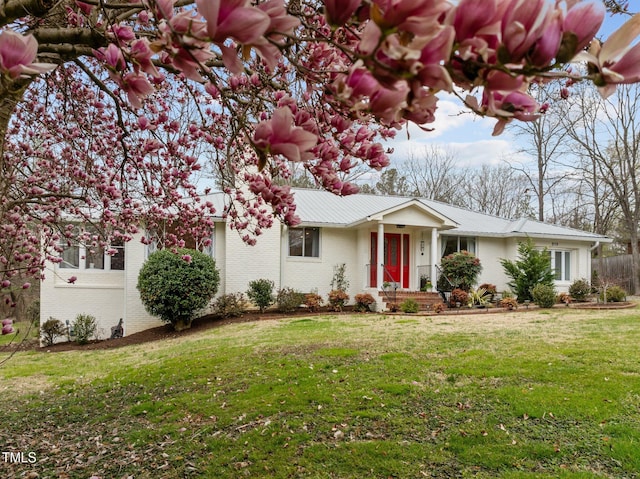 single story home featuring a front yard, metal roof, and brick siding