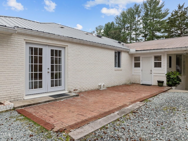 back of property with brick siding, a patio area, french doors, and metal roof