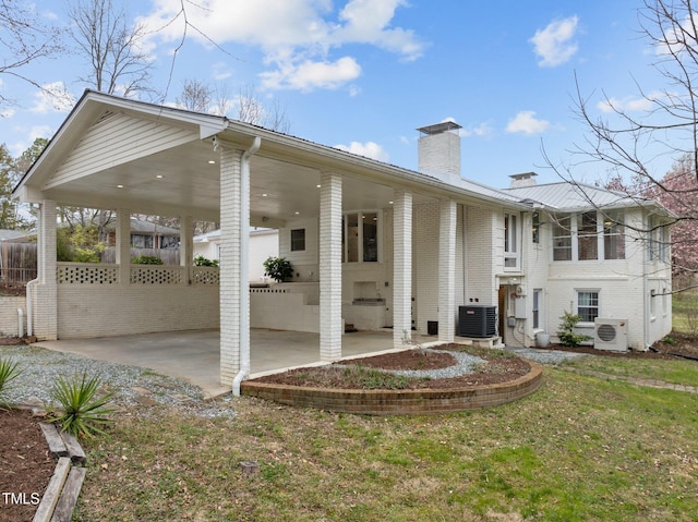 rear view of property featuring brick siding, ac unit, fence, and a chimney